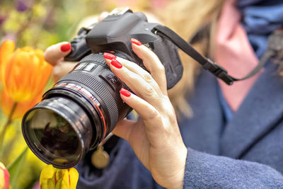 A middle-aged woman photographer takes pictures of spring flowers in the botanical garden