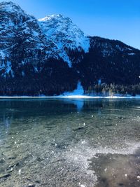 Scenic view of lake by snowcapped mountain against sky