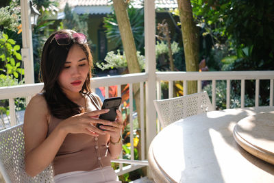 Young woman using mobile phone while sitting on camera