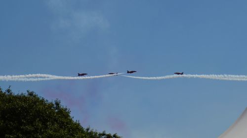Low angle view of red arrows airplane display team flying against sky