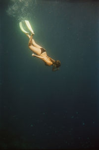 Woman free diving near nusa penida, bali, indonesia. nikonos v on 35mm cinestill 400d film.