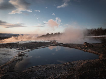 Smoke emitting from volcanic landscape against sky