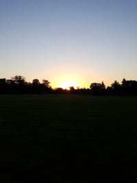 Scenic view of field against clear sky during sunset