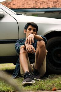 Portrait of young man sitting by car