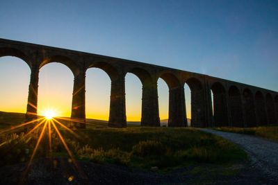 Arch bridge against clear sky during sunset