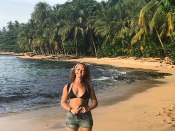 Portrait of smiling young woman on beach against sky