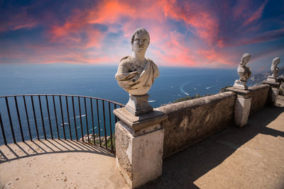 Statue by sea against sky during sunset