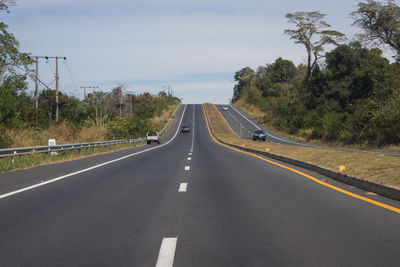 Highway amidst trees against sky