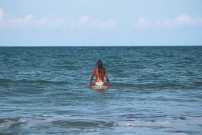 Woman in sea against sky