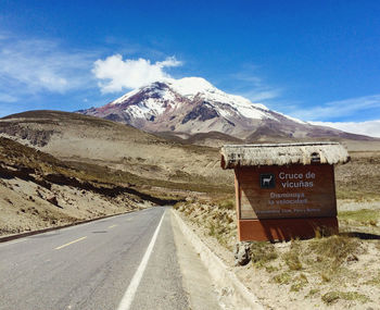 Road leading towards snowcapped mountains against sky