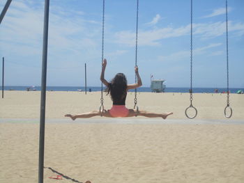 Rear view of woman doing gymnastics at beach