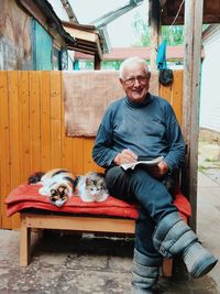 Portrait of smiling man with cats sitting outdoors