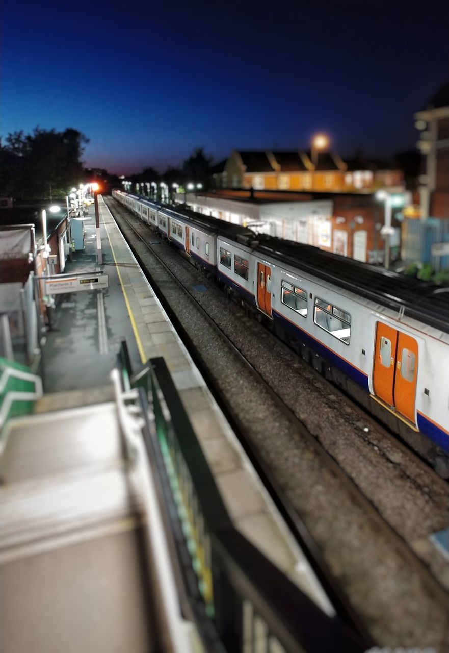 rail transportation, mode of transportation, transportation, railroad track, train, track, train - vehicle, public transportation, selective focus, illuminated, night, no people, passenger train, sky, high angle view, motion, travel, outdoors, railroad station, business, shunting yard, station