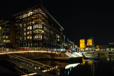 Illuminated light trails on bridge over river in city at night