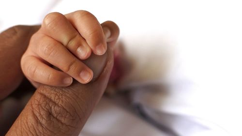 Cropped hand of newborn holding father finger