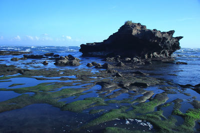 Rocks on sea shore against sky