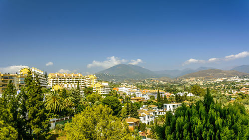 Panoramic shot of trees and cityscape against clear blue sky