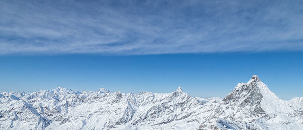 Scenic view of snowcapped mountains against blue sky