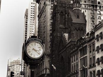 Low angle view of clock by buildings in city