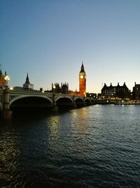 Bridge over river in city against clear sky