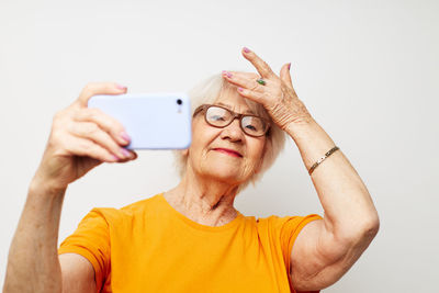 Portrait of woman holding smart phone against white background