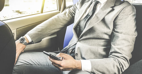 Midsection of businessman using mobile phone while sitting in car