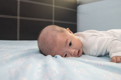 Portrait of cute baby lying on bed at home