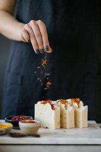 A woman's hand sprinkles saffron on the craft soap. 