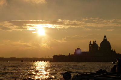 Silhouette of temple by river during sunset