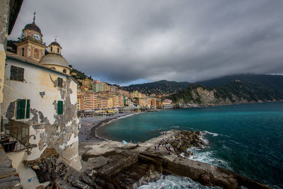 Scenic view of sea by buildings against cloudy sky