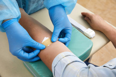 Cropped hands of nurse applying bandage on patient hand