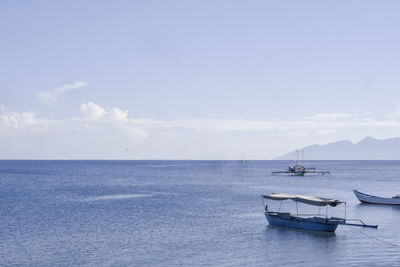 Fishing boats in sea against sky