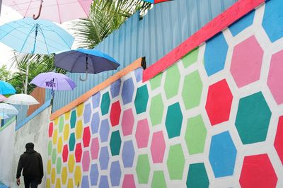 Low angle view of multi colored umbrellas hanging against building