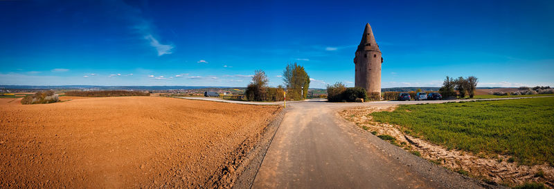Panoramic view of road amidst land against blue sky