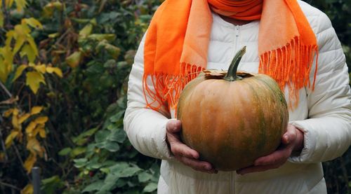 Midsection of woman holding pumpkin