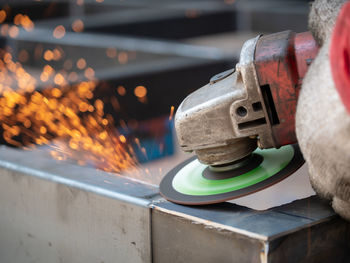 Low angle view of illuminated industry. worker grinding cutting metal sheet grinder machine welding 