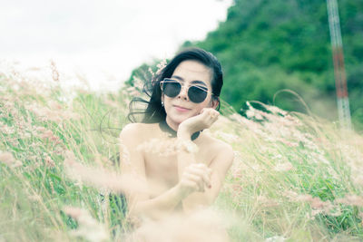 Portrait of young woman wearing sunglasses on field