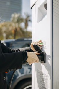 Woman plugging electric car charger at charging station