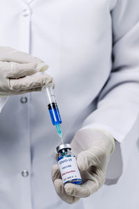 Midsection of doctor holding syringe and vial