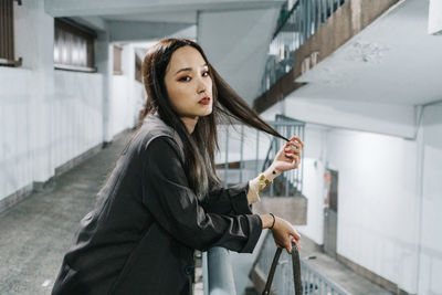 Side view of young woman standing by railing