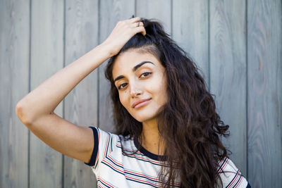 Portrait of young woman standing against wooden wall