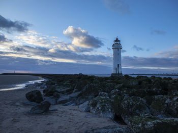 Lighthouse by sea against sky