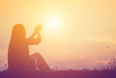 Woman photographing at sunset