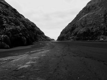 Road amidst rocky mountains against sky