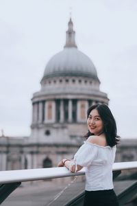 Portrait of young woman in front of building