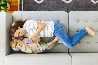 High angle view of mother and daughter sitting on sofa at home