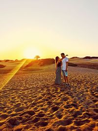 Couple kissing on land against sky during sunset