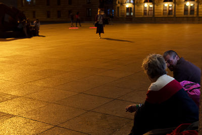 Rear view of couple sitting on street