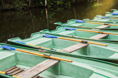 Green old empty boats with wooden oars on the lake closeup. recreational old row boats.