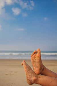 Midsection of person on beach against sky